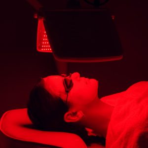 Young woman having red LED light facial therapy treatment in beauty salon. Beauty and wellness